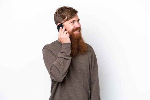 Homme rousse avec barbe isolé sur fond blanc en gardant une conversation avec le téléphone mobile