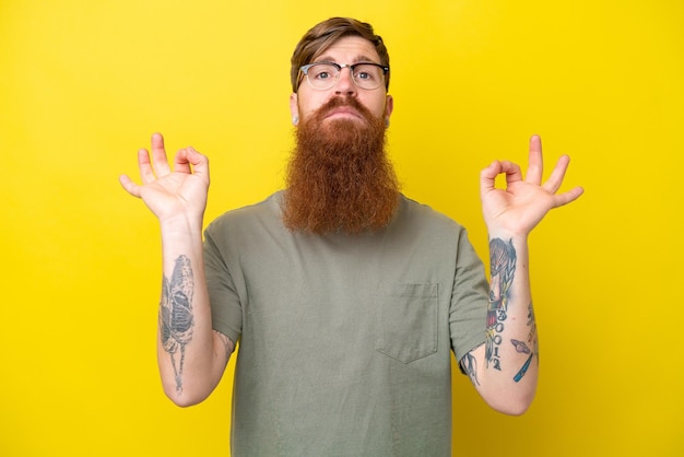 Homme rousse avec barbe isolé sur fond jaune dans une pose zen