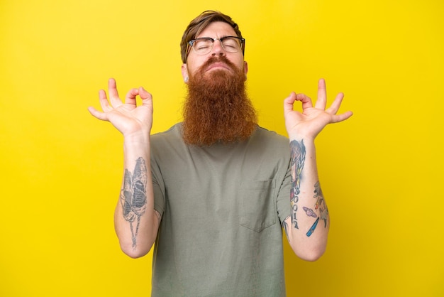 Homme rousse avec barbe isolé sur fond jaune dans une pose zen