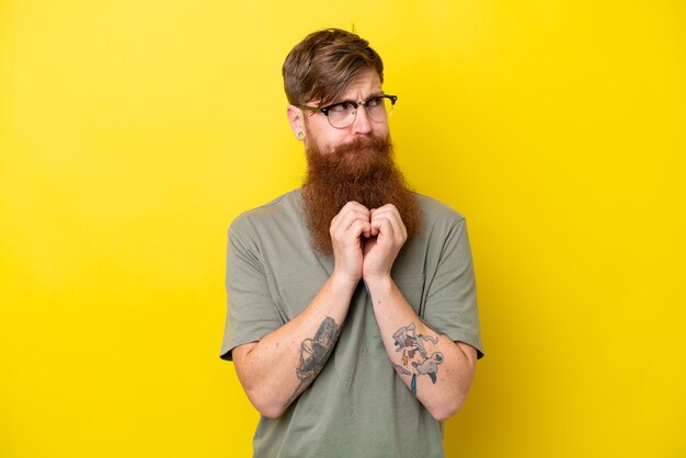 Homme rousse avec barbe isolé sur fond jaune intrigant quelque chose