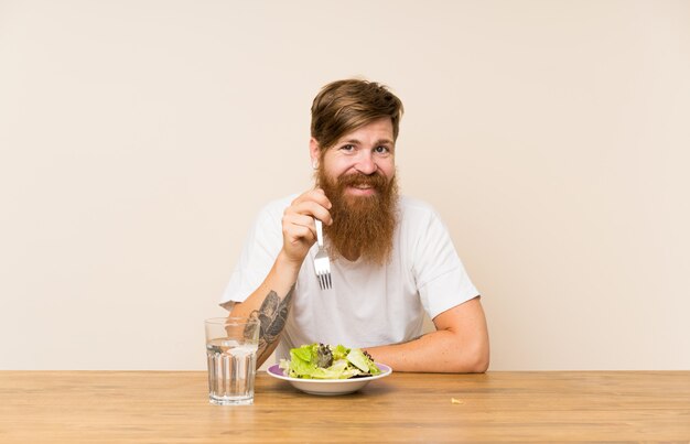 Homme rousse à la barbe longue et à la salade souriant