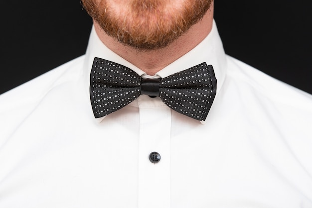 Homme rousse à barbe rousse vêtu d'un noeud papillon noir et d'une chemise blanche