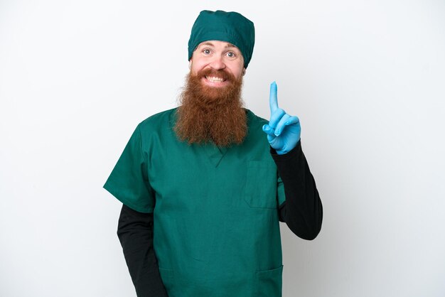 Homme rousse chirurgien en uniforme vert isolé sur fond blanc pointant avec l'index une excellente idée