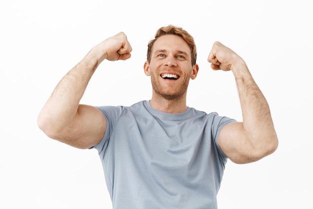 Homme rousse fort et beau avec un corps parfait levant les bras masculins et célébrant en regardant au-dessus du flux de jeu de sport et souriant heureux de gagner de l'argent triomphant et enracinant pour l'équipe