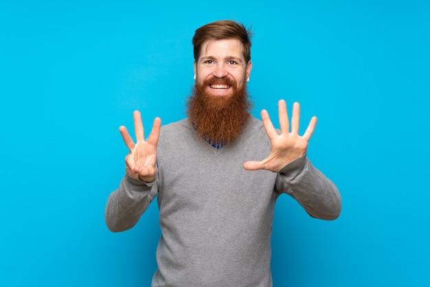 Homme rousse avec longue barbe sur bleu isolé comptant huit avec les doigts