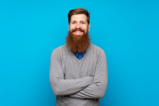 Homme rousse avec longue barbe sur bleu isolé en gardant les bras croisés en position frontale