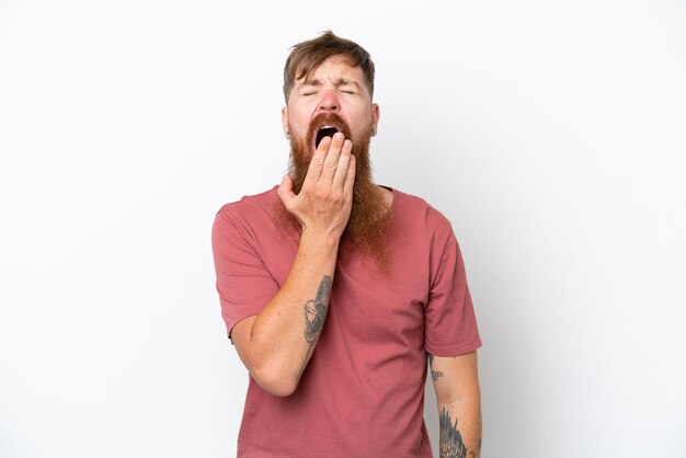 Homme rousse avec une longue barbe isolé sur fond blanc bâillant et couvrant la bouche grande ouverte avec la main