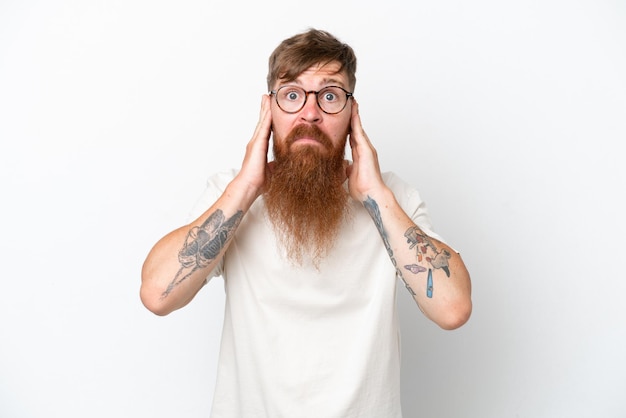 Homme rousse avec une longue barbe isolé sur fond blanc frustré et couvrant les oreilles