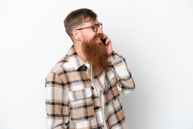 Homme rousse avec une longue barbe isolé sur fond blanc en gardant une conversation avec le téléphone mobile