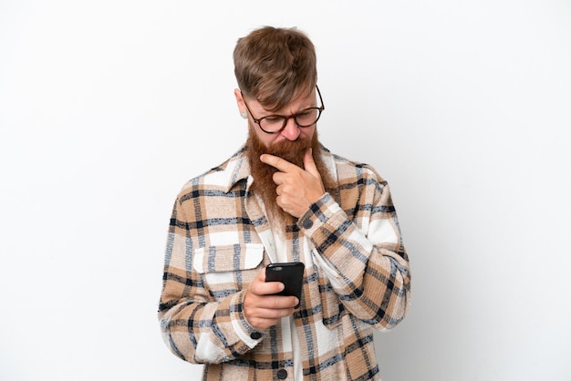 Homme rousse avec une longue barbe isolé sur fond blanc pensant et envoyant un message