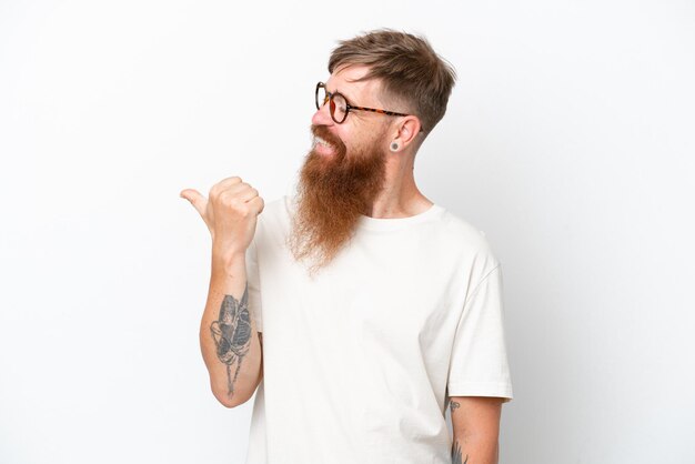 Homme rousse avec une longue barbe isolé sur fond blanc pointant vers le côté pour présenter un produit