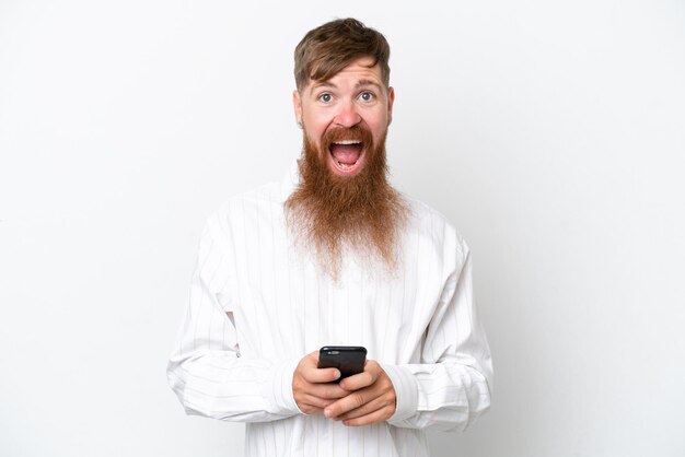 Homme rousse avec une longue barbe isolé sur fond blanc surpris et envoyant un message