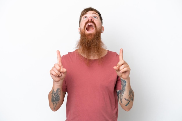 Homme rousse avec une longue barbe isolé sur fond blanc surpris et pointant vers le haut