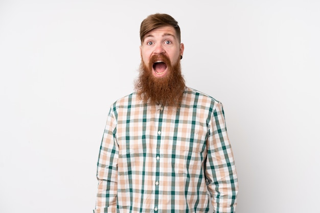 Homme rousse avec une longue barbe sur un mur blanc isolé avec une expression faciale surprise