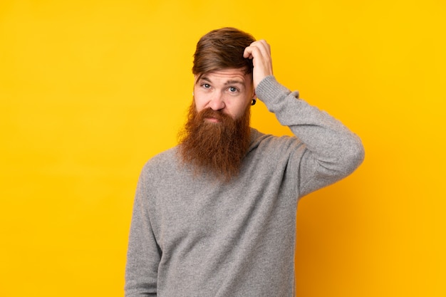 Homme rousse avec une longue barbe sur un mur jaune isolé avec une expression de frustration et de ne pas comprendre