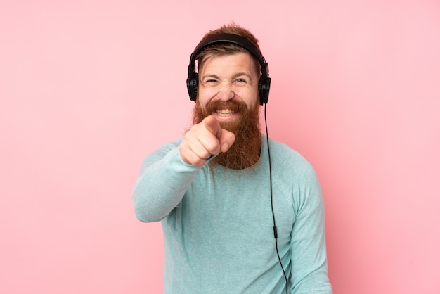 Homme rousse avec longue barbe sur mur rose isolé