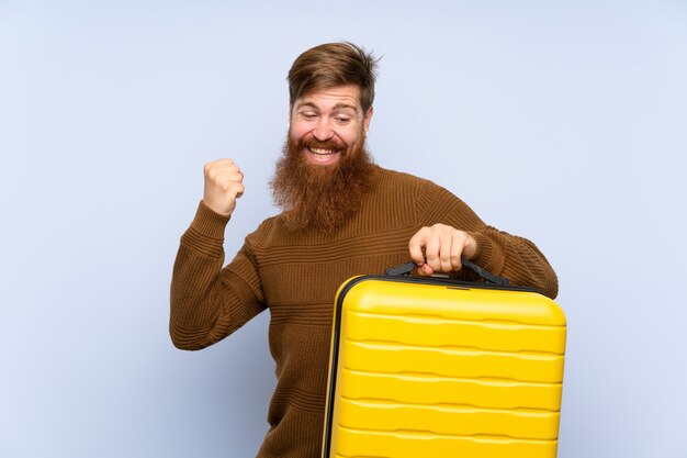 Homme rousse à la longue barbe tenant une valise célébrant une victoire