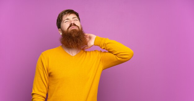 Homme rousse à longue barbe sur violet isolé avec maux de cou