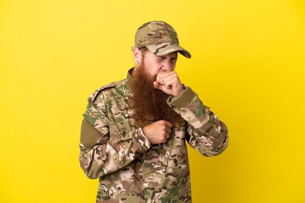 L'homme rousse militaire sur isolé sur fond jaune souffre de toux et se sent mal