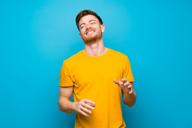 Homme rousse sur mur bleu souriant