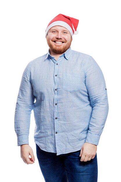 Homme rousse souriant au chapeau de père Noël. Célébration du nouvel an et de Noël. Isolé. Verticale.