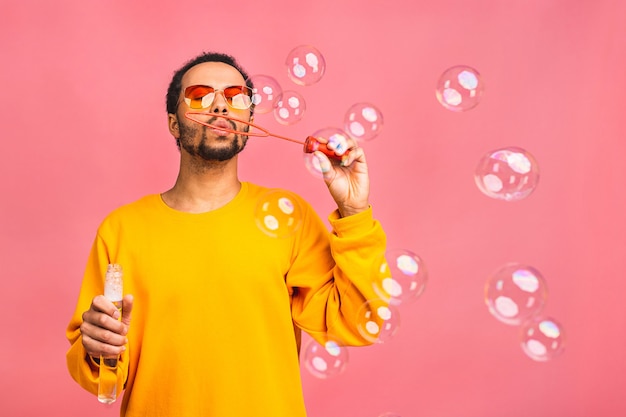 l'homme s'amuse avec des bulles de savon. Isolé sur rose