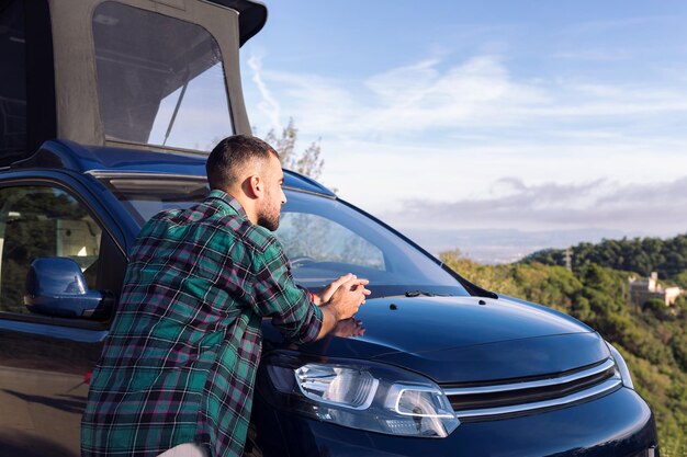 Homme s'appuyant sur son camping-car observant la nature