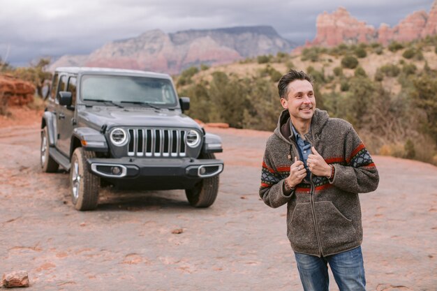 homme s'appuyant sur une voiture de sport souriant joyeusement