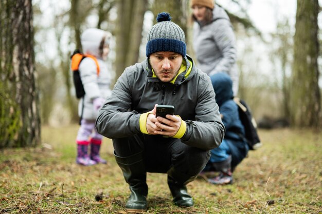 L'homme s'assit pour regarder le téléphone dans la forêt avec un visage surpris