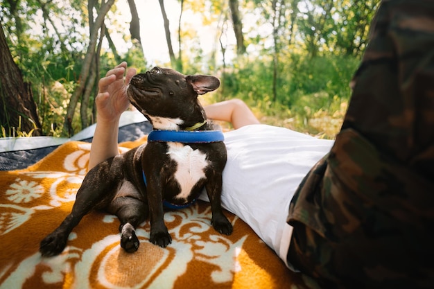 Photo un homme s'attache à un bulldog français allongé sur une couverture de pique-nique contre des arbres.