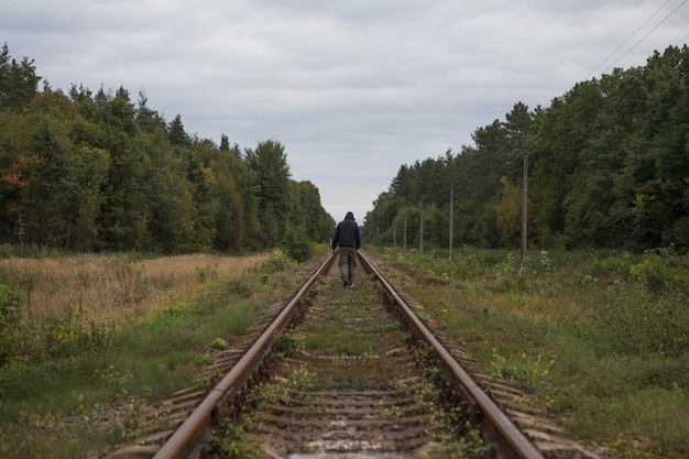 Un homme s'éloigne sur un chemin de fer avec une lumière chaude