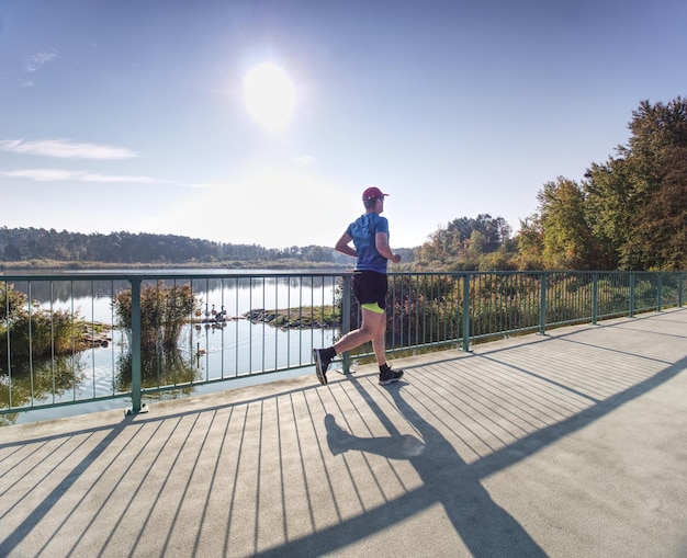 Photo l'homme s'entraîne dans la nature avec le soleil derrière lui jeune homme le matin court à l'extérieur