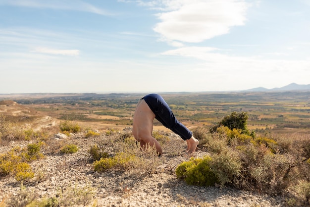 Un homme s'initiant et se positionnant en Salamba Shirshasana ou Yoga Headstand lors d'une séance de yoga à la campagne et dans la nature