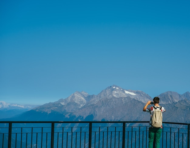 Homme avec sac à dos debout sur la terrasse d'observation dans les montagnes