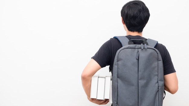 Homme avec sac à dos d'école et tenant des livres stand retour copie espace fond blanc