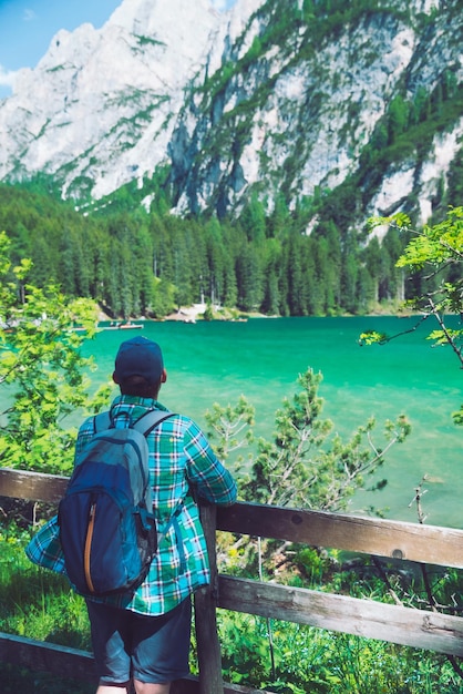 Homme avec sac à dos regardant le lac dans les montagnes des dolomites