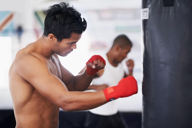 Photo homme de sac de frappe et de boxe en forme dans un gymnase pour l'entraînement de la résilience ou de la performance corps sportif et profil de boxeur masculin avec pratique de coups de poing pour la force énergie pour l'exercice de combat