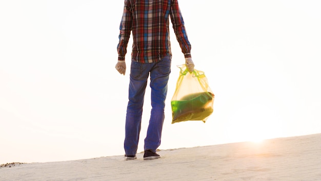 Un homme avec un sac à ordures nettoie la zone des ordures