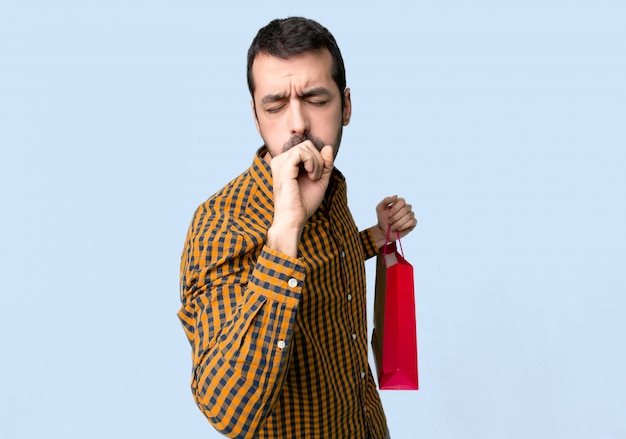 Homme avec des sacs à provisions souffre de toux et se sentir mal sur fond bleu isolé