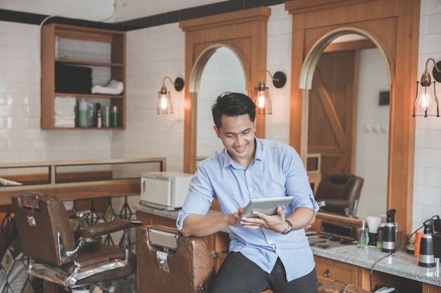 Homme en salon de coiffure avec tablette numérique