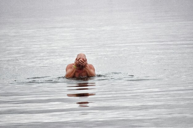 Photo un homme sans chemise nageant dans la mer.