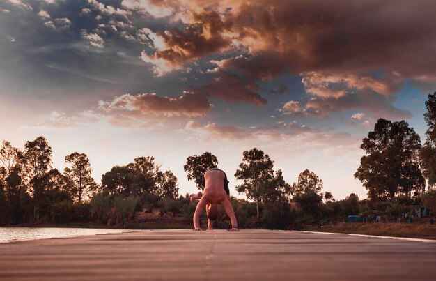 Photo un homme sans chemise pratiquant le yoga sur le quai contre le ciel au coucher du soleil