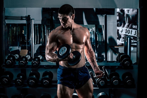 Un homme sans chemise s'entraîne avec un haltère au gymnase.