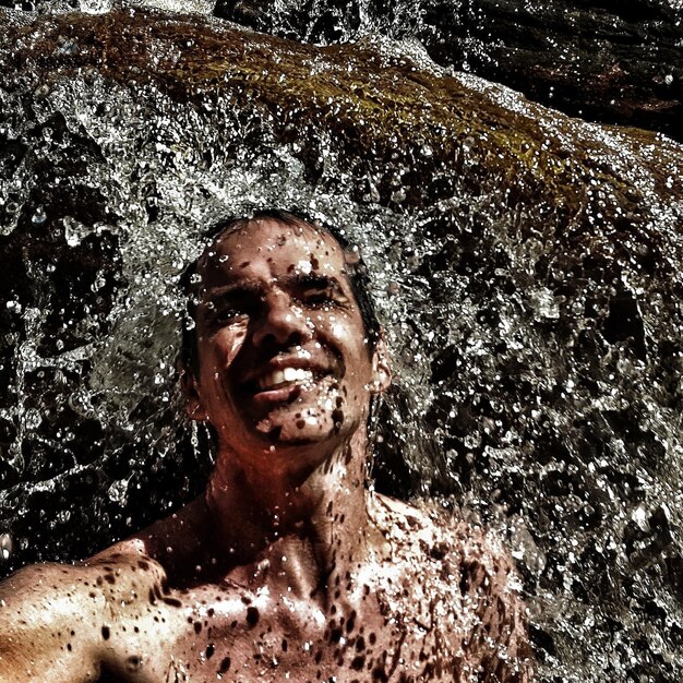 Photo un homme sans chemise sous une cascade.