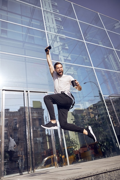 Homme sautant dans la rue avec un smartphone