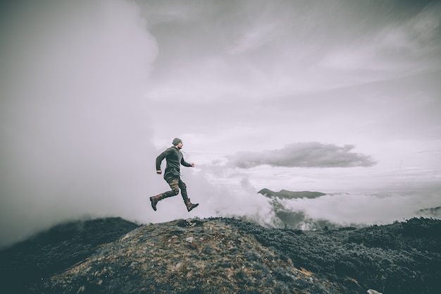 L'homme sautant sur la montagne sur un beau fond de nuages