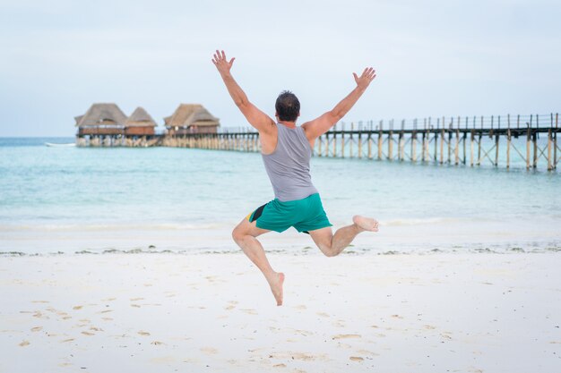 Homme sautant sur la plage tropicale