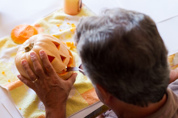 homme sculptant une citrouille