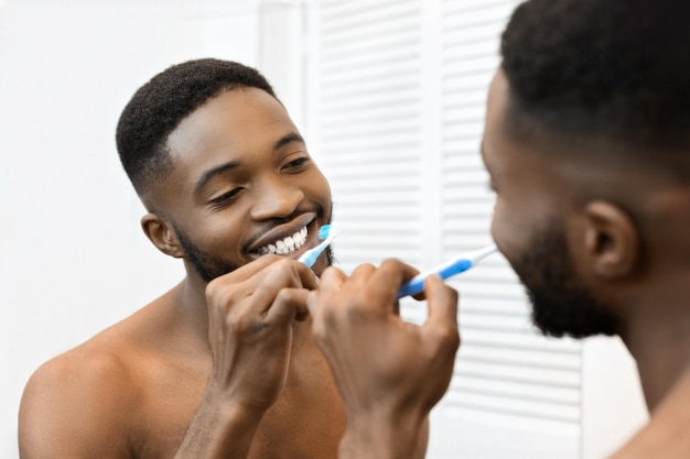 Photo un homme se brosse les dents devant le miroir de la salle de bain.