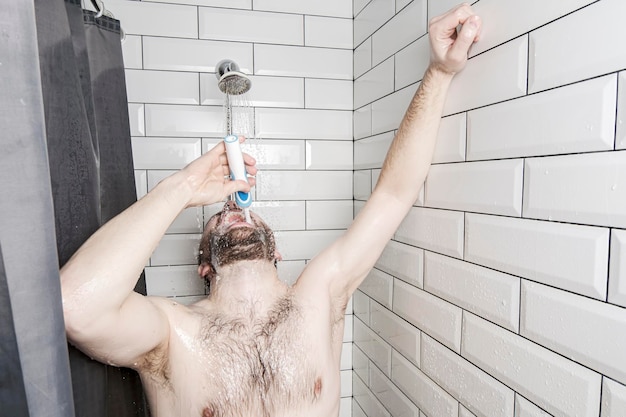 L'homme se brosse les dents lavable avec une brosse à dents rechargeable et en même temps